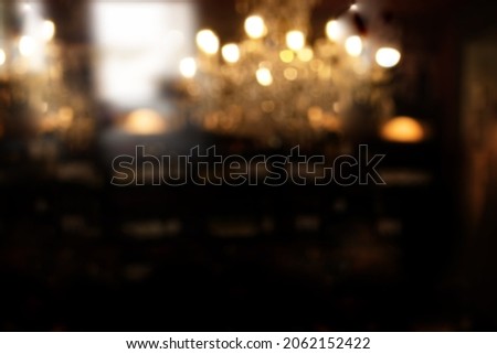 Dark blurred restaurant background with golden bokeh. Abstract background for gastronomy and cafe. Royalty-Free Stock Photo #2062152422