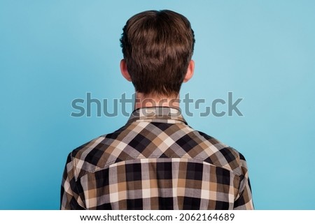 Rear behind view photo of brunette guy standing turned back not showing face isolated blue color background
