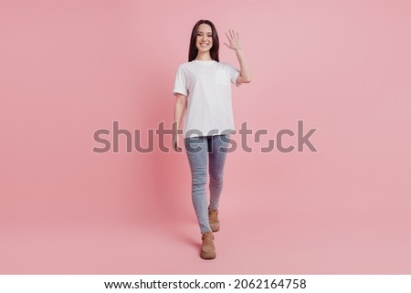 Full body photo of young attractive woman go waving hand hello meet friend isolated over pink color background