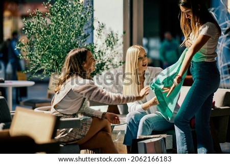 Three shopaholics are sitting at a coffee shop and showing each other clothing they bought for a special occasion. Royalty-Free Stock Photo #2062166183