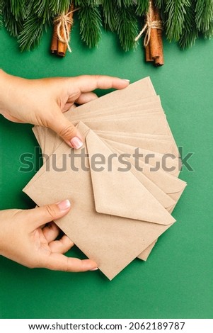 woman hands hold stack of craft beige envelopes, concept of sending Christmas greetings. 