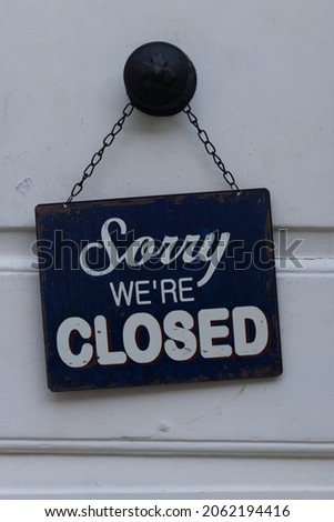 Sorry we are closed sign hanging on a white store doors