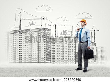 Young man in hardhat and construction sketches at background