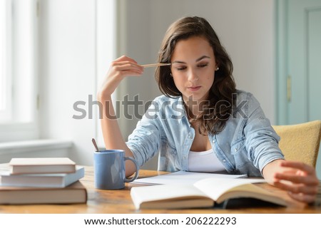 Teenage girl studying reading book at home concentrating looking down Royalty-Free Stock Photo #206222293