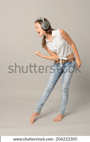 Singing girl with headphones enjoy dance full length gray background