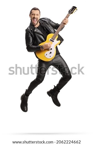 Man in leather clothes playing an electric guitar and jumping isolated on white background  Royalty-Free Stock Photo #2062224662