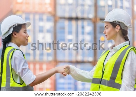 Group of factory worker women meeting to inspect containers logistic in warehouse. Asian, and white caucasian people make a deal and shaking hands on site cargo for logistic shipping area.