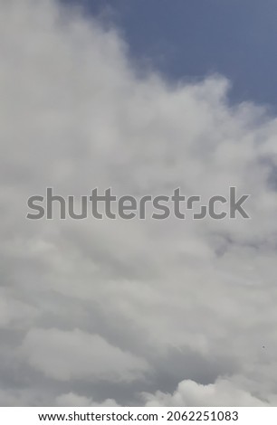 Vertical picture of white clouds covering up the blue sky in the afternoon