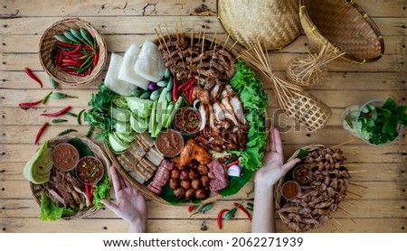Isan food set. GRILLED PORK WITH PICKLED FISH SAUCE and spicy sauce. Fresh vegetables and chili Surf on the banana leaf in wooden tray Royalty-Free Stock Photo #2062271939