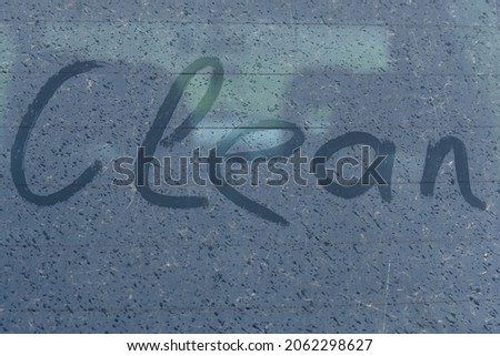 Ecology concept. On the dirty glass, raindrops and the inscription - clean made by your finger