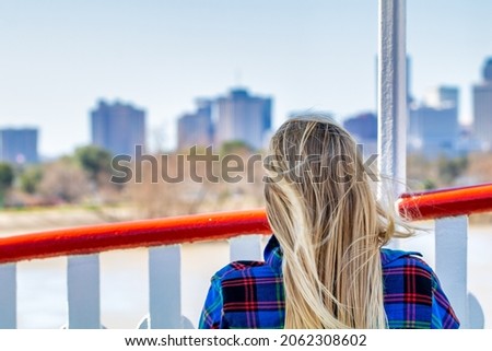 Beautiful blonde woman enjoying New Orleans skyline, back view on a sunny day