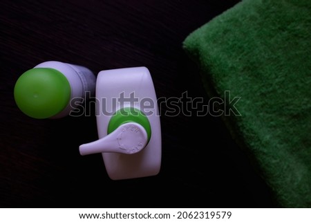 Hygiene supplies on a dark wooden background. Cream, green towel in the bathroom.