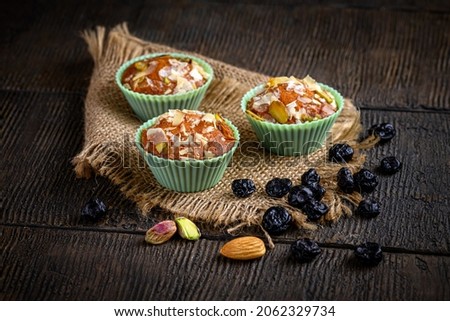 Mawa Muffin Cake is a rich, delicious cake made with mawa and atta. Serve on wooden texture background with blackberry dry fruit nuts. Homemade muffin cake. Almond, Cashew, Blackberry, Pistachio. Royalty-Free Stock Photo #2062329734