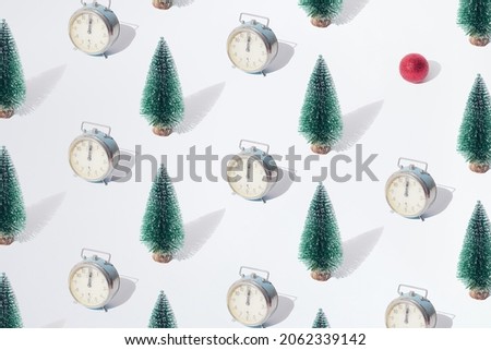 Arranged green New Year and Christmas tree with old silver retro watch with hand on twelve midnight hour and red bauble on a white pastel background. Pattern.