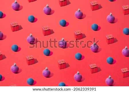 Arranged New Year and Christmas blue and purple  bauble and gift box on a red pastel background. Pattern.