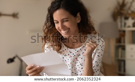 Happy excited woman reading paper letter and getting unbelievable good news, making yes winner hand gesture, celebrating loan or statement approval, job achieve, promotion, success Royalty-Free Stock Photo #2062352324