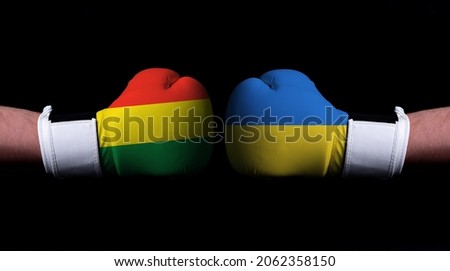 Two hands of wearing boxing gloves with Ukraine and Bolivia flag. Boxing competition concept. Confrontation between two countries
