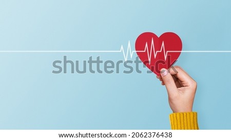 Woman hand holding red paper heart with cardiogram on blue background. Concept of valentines day, love, health care Royalty-Free Stock Photo #2062376438