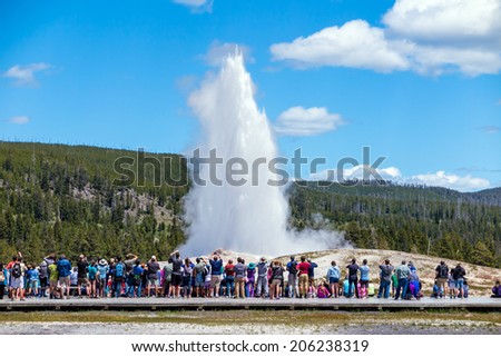 Tourists watching the Old Faithful erupting in Yellowstone National Park, USA Royalty-Free Stock Photo #206238319