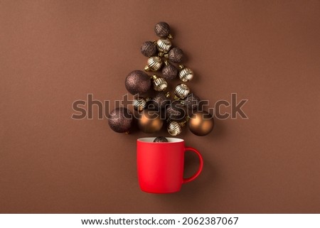 Top view photo of brown silver and gold christmas tree balls flying out of red cup on isolated brown background