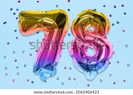 Rainbow foil balloon number, digit seventy eight on a blue background with sequins. Birthday greeting card with inscription 78. Top view. Numerical digit. Celebration event, template.