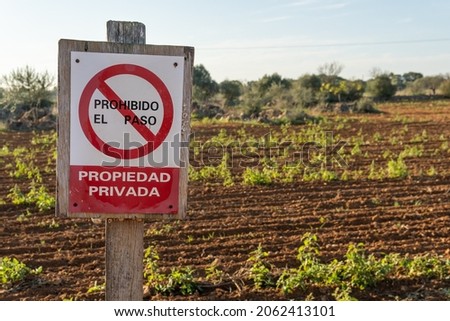 Close-up of a private property and no trespassing sign, written in Spanish, in a rural field at dawn