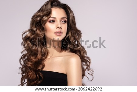 Brunette  girl with long  and   shiny curly  hair .  Beautiful  model woman  with wavy hairstyle 