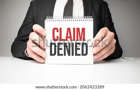 Businessman holding sheet of paper with a message Claim Denied