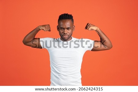 Power, strength. Portrait of African young man in casual clothes isolated on red color studio background. Concept of human emotions, facial expression, youth, sales, diversity. Copy space for ad.