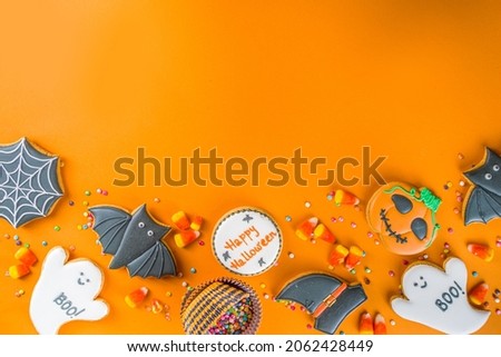 Halloween treats background with sugared Gingerbread cookies and candies, Trick or treat concept top view copy space, trendy bright orange color background