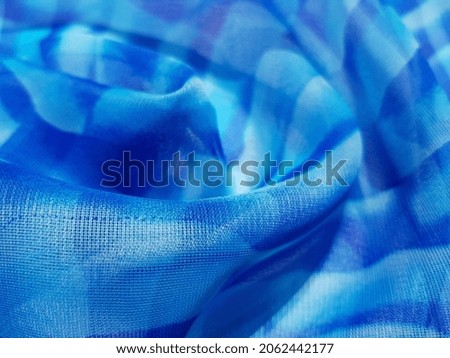 Light blue translucent striped fabric in folds (macro, texture).