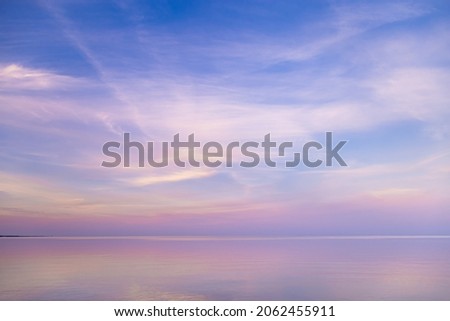 Beautiful sunset on sea, pastel colors and reflections on water, calm nature landscape with colorful clouds and sea. Environment natural gradient. Abstract background. 