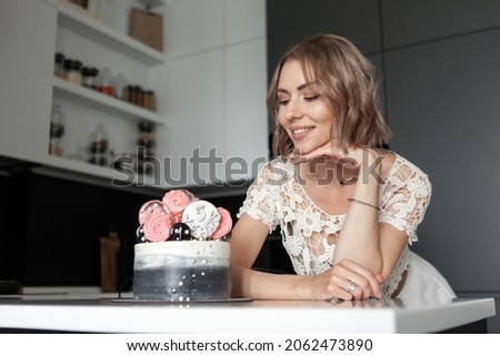 Smiling beautiful woman looks at the cake in the kitchen. Birthday or anniversary