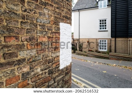 Large painted white marker seen open the Sid of an old wall to a house. Located on a narrow, sharp bend in an English city centre, to help prevent vehicles hitting the wall.