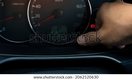 Rider uses his thumb to press the reset button on the speed meter. In the state where the car is parked