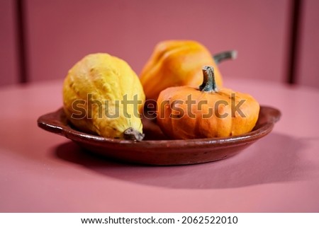 Three decorative pumpkins on a ceramic plate.