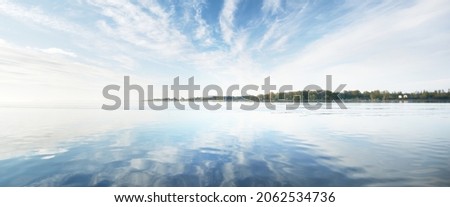 Baltic sea after the rain at sunset. Dramatic blue sky with cirrus clouds, symmetry reflections in the water. Abstract natural pattern, texture, background, concept art