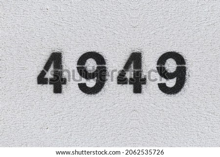 Black Number 4949 on the white wall. Spray paint. Number four thousand nine hundred forty nine.