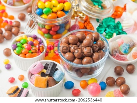 Milk chocolate candies in shell with jelly sugar gums and liquorice allsorts and fruit sherbet candies on white background. with marshmallows and strawberry bon bons. Royalty-Free Stock Photo #2062536440