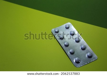 Pills in packs on a yellow-green background.