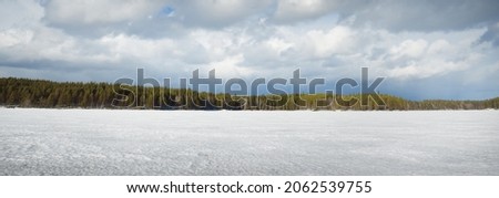 Frozen lake and pine forest at sunset. Ice texture. Dramatic stormy blue sky, epic cloudscape. Winter wonderland. Nature, ecology, climate change, ecotourism, fickle weather