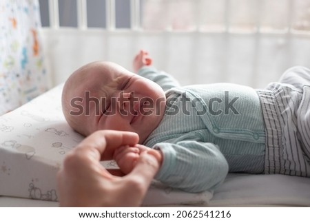Crying caucasian baby on a bed suffering from colic pain. Royalty-Free Stock Photo #2062541216