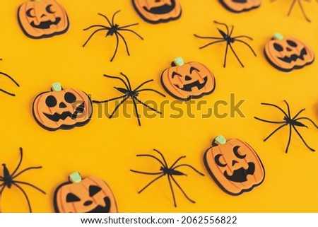 Halloween background. Modern pumpkins jack o lantern and spiders layout on orange background. Happy Halloween festive pattern. Halloween decorations on yellow paper