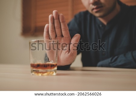 Alcoholism, sad depressed asian young man refuse, push alcoholic beverage glass, drink whiskey, sitting alone at night. Treatment of alcohol addiction, having suffer abuse problem alcoholism concept. Royalty-Free Stock Photo #2062566026