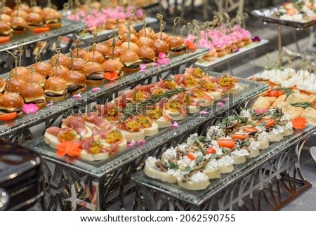 A set of canapes and snack at a banquet with white table. Slices of tomato, olive, cheese, bread and fish on food stand