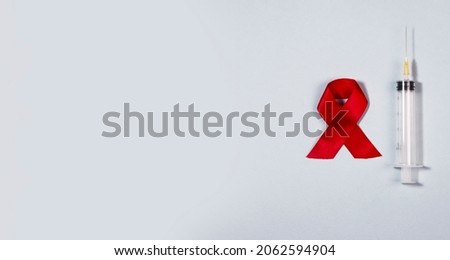 Clean syringe and red ribbon bow as symbol of AIDS and HIV awareness day. Medical banner.