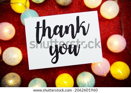 Thank You text on paper card top view on red bokeh background