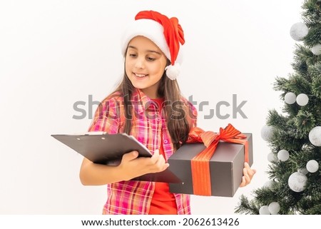 Smiling funny child in Santa red hat. Holding Christmas gift in hand. Christmas concept. on white background