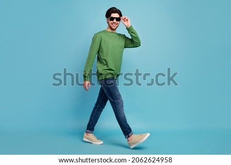 Full body photo of young handsome smiling man wear sunglass go walk traveling summer isolated on blue color background