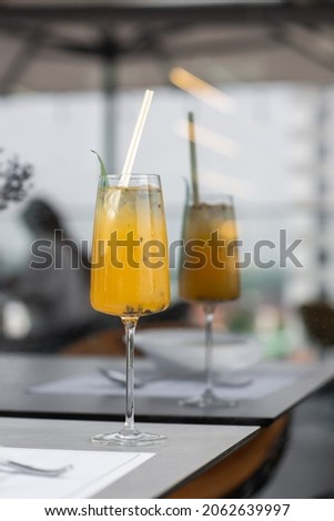 Glass with yellow lemon and passion fruit cocktail decorated with dried pineapple and mint on the bar on a bright background.